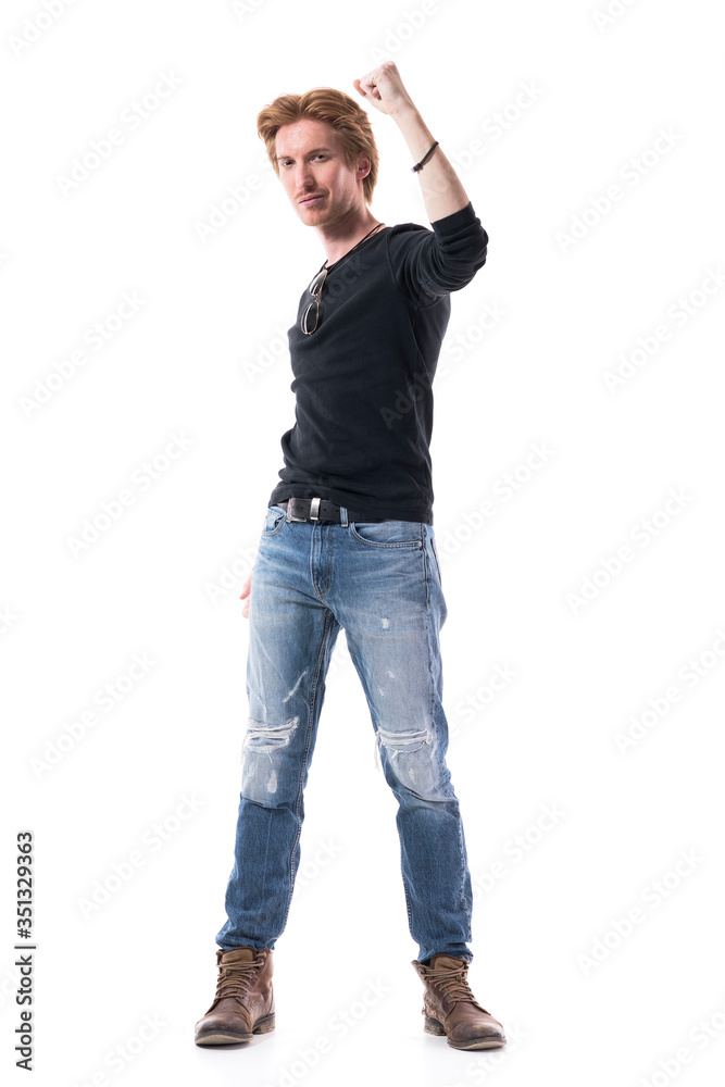 Confident successful young stylish redhead man with raised arm and clenched fist celebrating. Full body length isolated on white background. Confident successful young stylish redhead man with raised arm and clenched fist celebrating. Full body length isolated on white background.