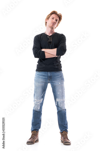 Cocky young stylish man with crossed hands looking at camera frowning with defensive attitude. Full body length isolated on white background. 