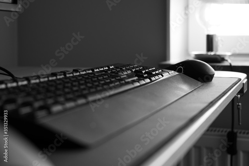 A black and white photo of a keyboard and mouse on a desk with no people in a home office. Showing the feeling of loneliness when working from home during quarantine