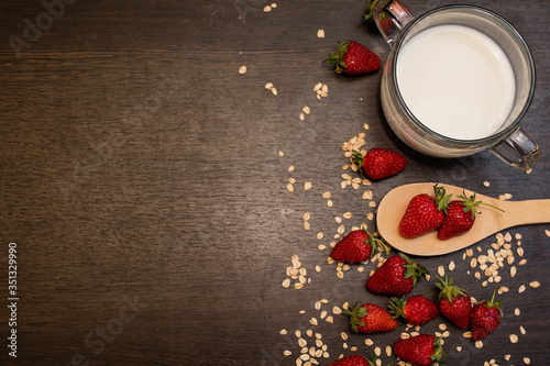 Oatmeal and strawberries on a brown background, strawberries and milk on a background