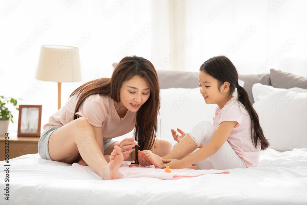 Happy mother and daughter applying nail polish in bedroom Happy mother and daughter applying nail polish in bedroom