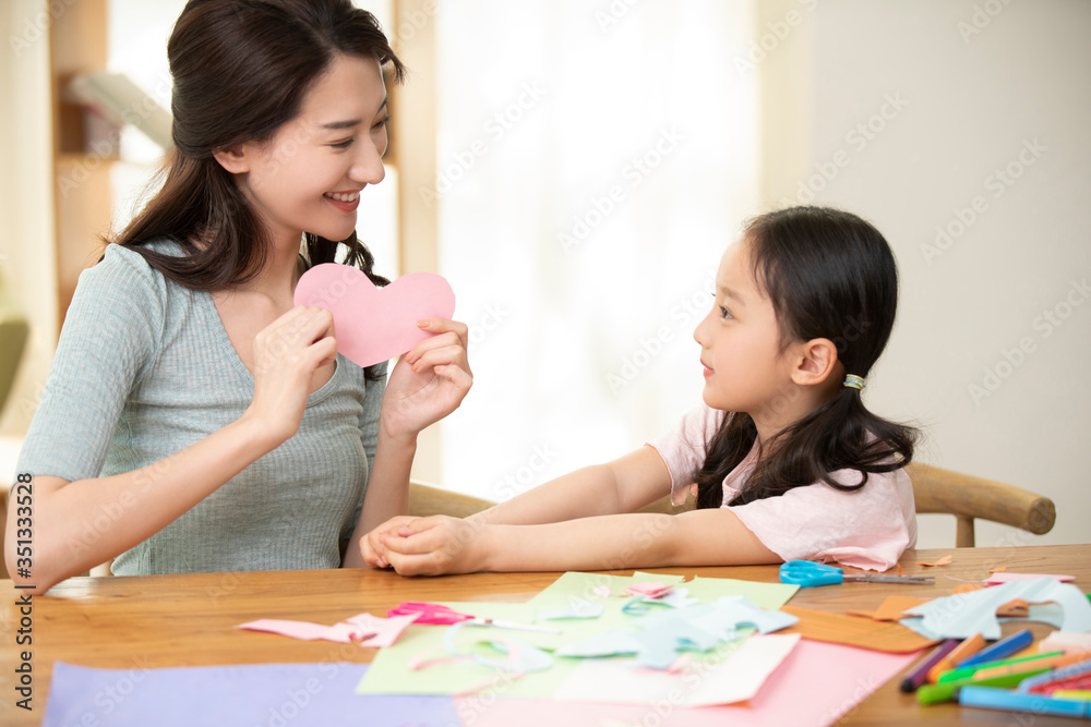 Happy mother and daughter cutting paper at home Happy mother and daughter cutting paper at home