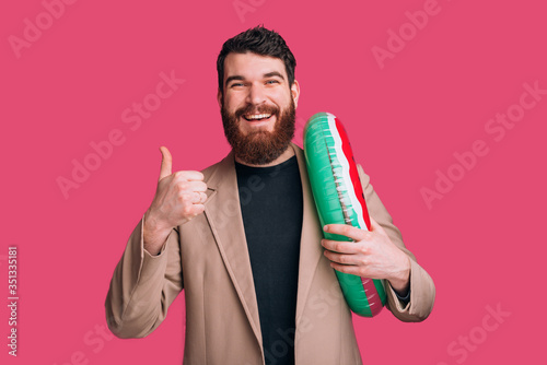 man about summer time is showing thumb up and holding a watermelom life saving ring. photo