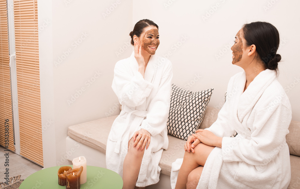 Two women talk nicely after applying a therapeutic mud mask to their faces. Spa treatments at the resort. Part of a series with mud mask