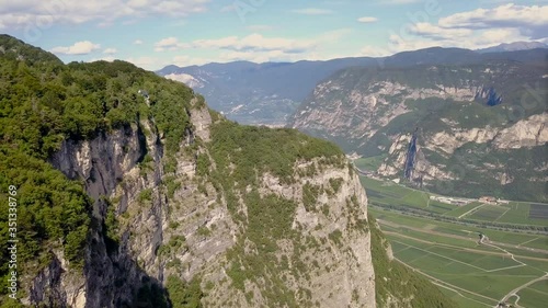 Cinematic Drone shot of a beautiful cliff on a mountain in Trentino Italy. The green mountain landscape is stunning on a bright day photo