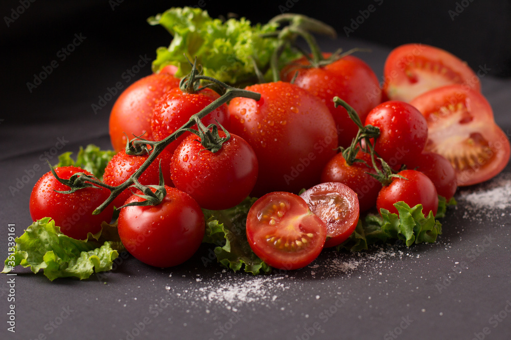 The fresh tomato with young herbs on a black background. The fresh tomato with young herbs on a black background.