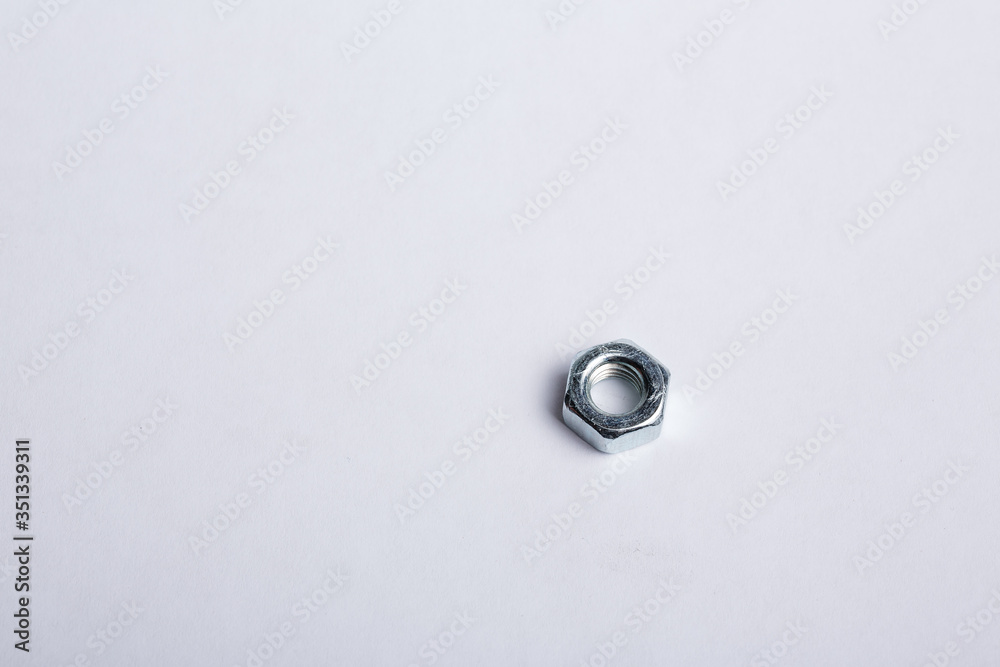One isolated chrome nut lies on a plain white background. Macro shot of parts for repair. Space for text One isolated chrome nut lies on a plain white background. Macro shot of parts for repair. Space for text