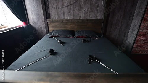 BDSM Leather handcuffs for role-playing games on a gray sheet. Bondage for carnal pleasures. Domination and submission. Departing camera. No people photo