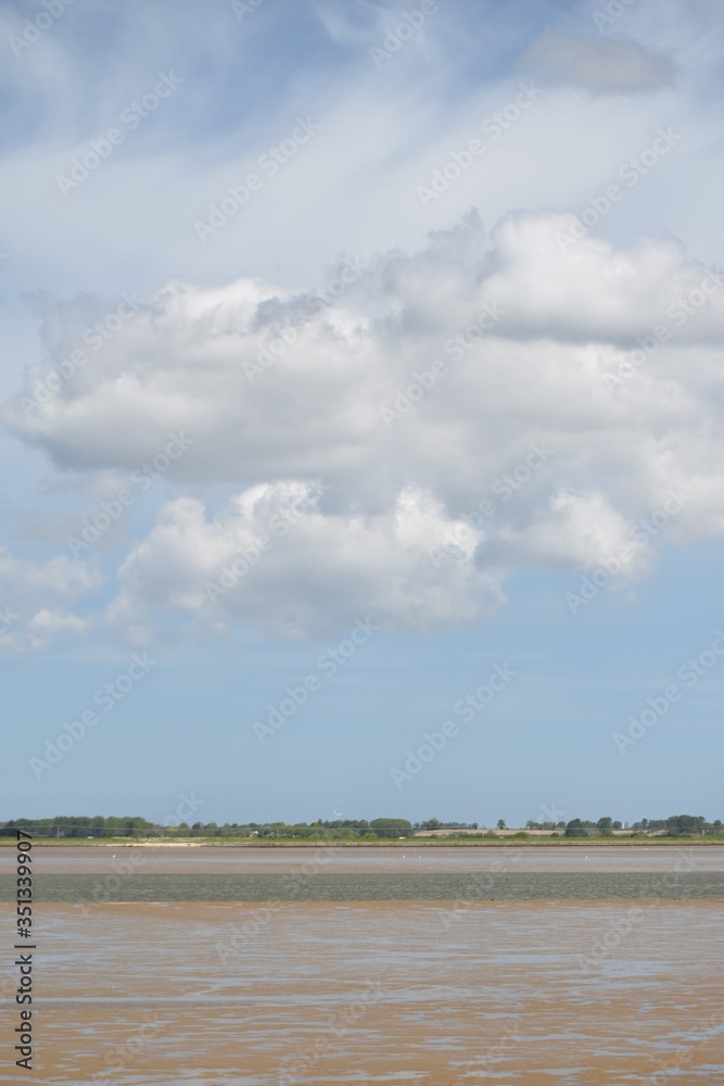 Obraz premium Cloudy skies over Breydon Water, a stretch of the River Yare in Great Yarmouth, Norfolk, UK.