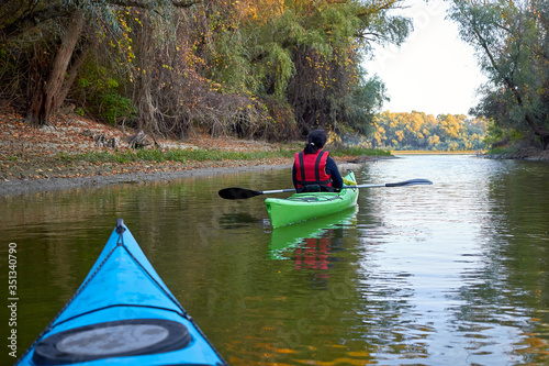 Kayaking together. Couple kayaking on the river together at autumn. View from blue kayak