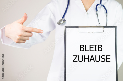 the word BLEIB ZUHAUSE "stay at home in English" woman doctor shows stay at home 