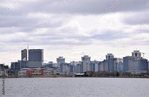 panorama of modern buildings across the river against a dark gray sky  urban architecture  urbanization