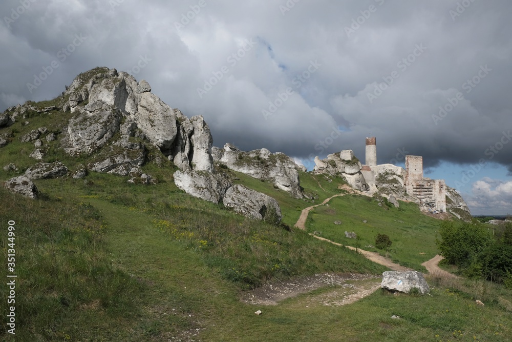 Beautiful ruin of castle on rocky hill with dramatic clouds in background. Olsztyn Castle on Eagles Nests trail. Medieval fortress in the Jura region near Czestochowa. Poland.