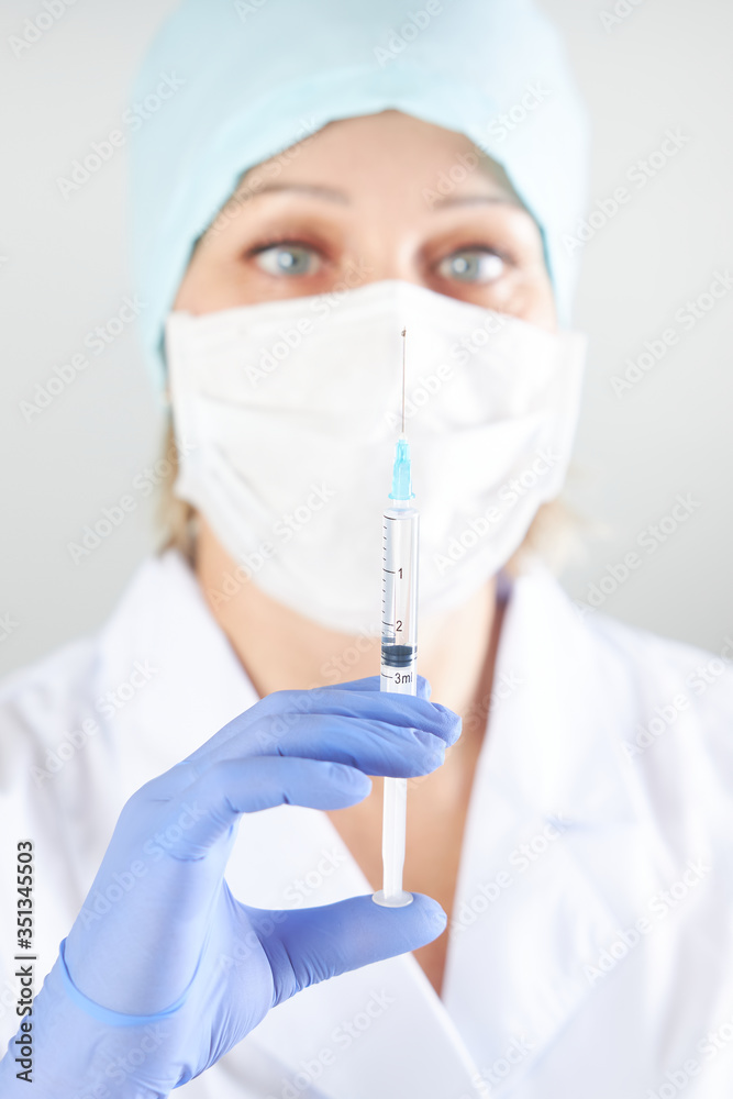 Syringe with medicine in hand on the background of the face of a female doctor Syringe with medicine in hand on the background of the face of a female doctor