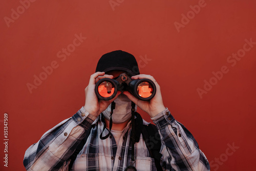 a man in a shirt look at the camera through binoculars on a red background