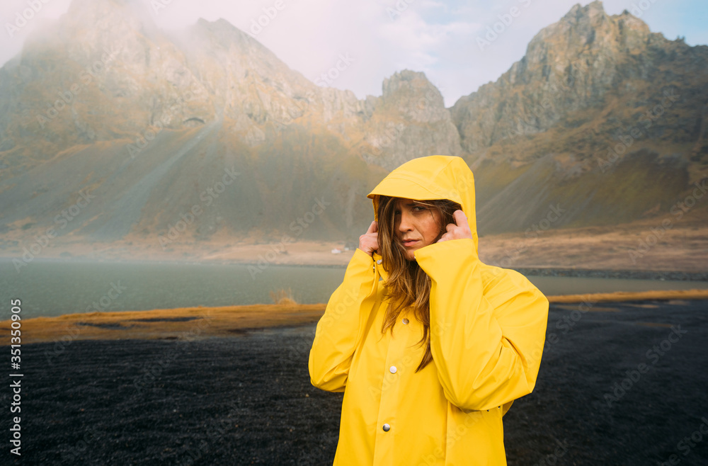 Portrait of woman wearing yellow coat standing at beach in Hvalnes Nature Reserve Beach, Iceland Portrait of woman wearing yellow coat standing at beach in Hvalnes Nature Reserve Beach, Iceland