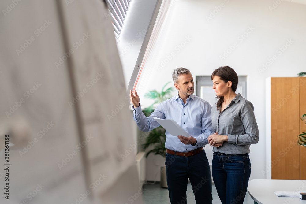 Businessman and businesswoman discussing paper in office Businessman and businesswoman discussing paper in office
