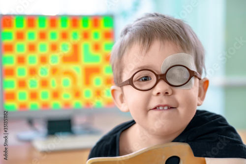 Foto A little boy wearing glasses and an eye patch (plaster, occluder)