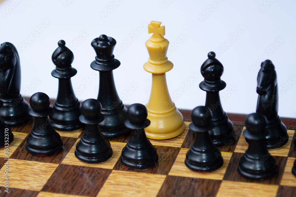 White king surrounded by a group of black pieces on a chessboard White king surrounded by a group of black pieces on a chessboard