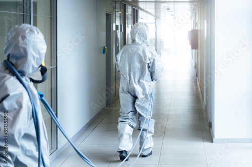 Cleaning staff desinfecting hospital against contageous virus, wearing protective clothing photo