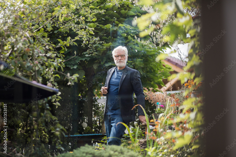 Senior man smoking cigarette in the garden Senior man smoking cigarette in the garden