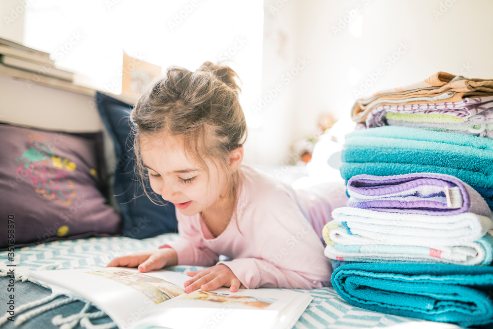 Little girl lying down looking at book Little girl lying down looking at book