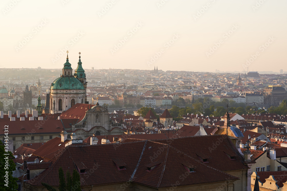 Cityscape picture of Prague, capitol of Czech republic taken from prague castle. Main subject is tower of Saint Nicolas church in Lesser town. Picture is taken in golden hour just after sunrise.