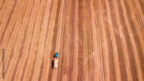 aerial view modern agricultural equipment , machinery, tractor harvests wheat field. seasonal works. drone shot. picture with space for text. Farmland from above