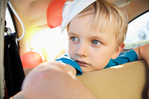 Germany, North Rhine Westphalia, Cologne, Boy in car with easter bunny mask, looking away photo