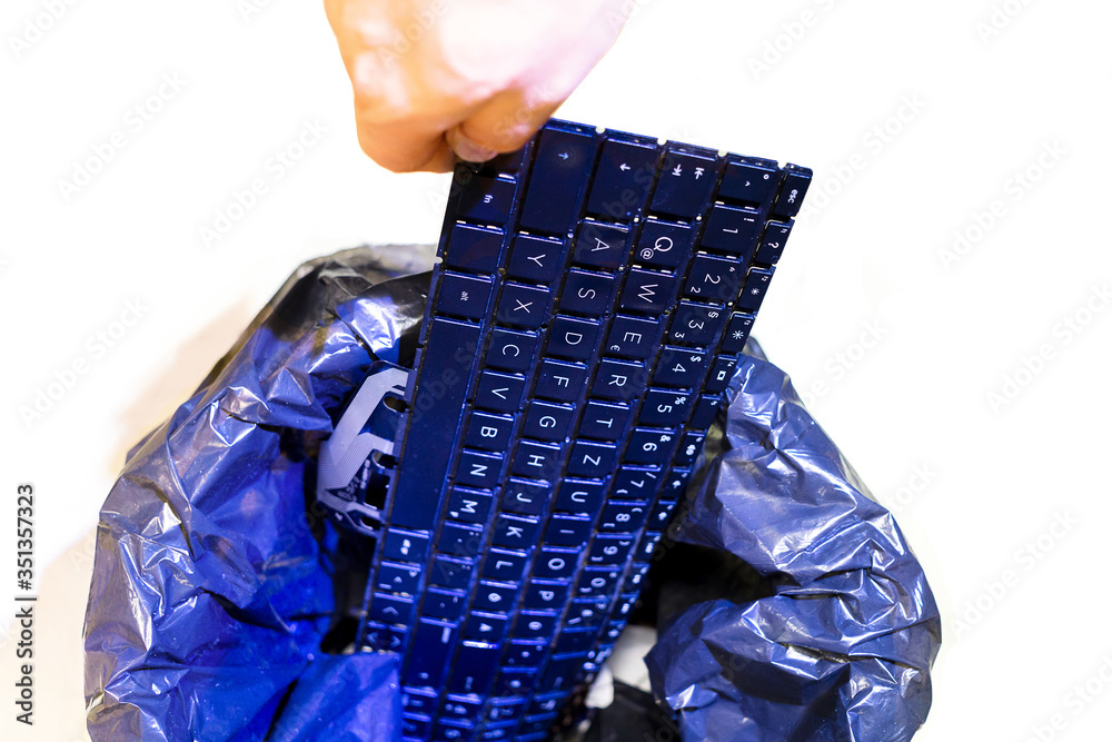 Male hand puts keyboard in office trash. Isolated garbage can, top view