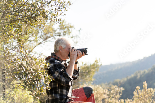 Senior man photographing in nature photo