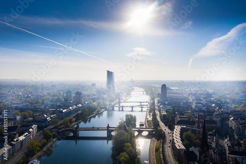 Germany, Hesse, Frankfurt, Helicopter view of sun shining over river Main and surrounding city buildings