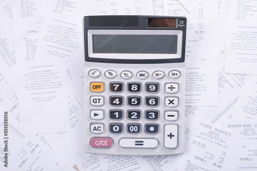 Calculator for counting on a pile of checks from purchases from the store on a wooden background. Top view. Place for text.Copy space Calculator for counting on a pile of checks from purchases from the store on a wooden background. Top view. Place for text.Copy space