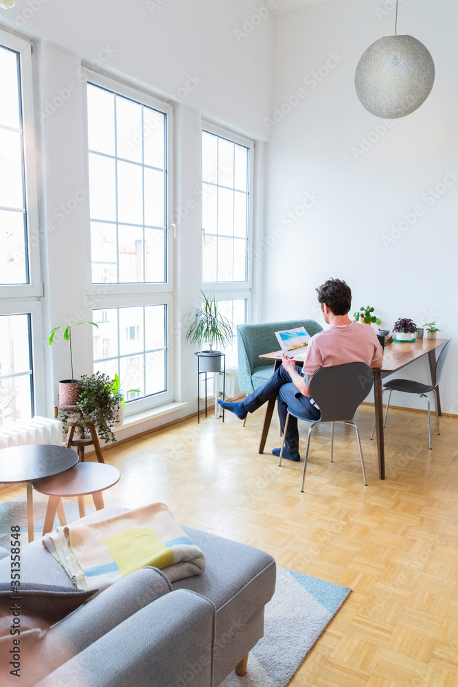 Man sitting at table at home looking at photographs Man sitting at table at home looking at photographs