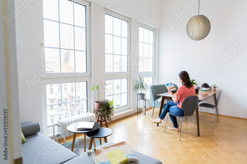 Woman sitting at table at home looking at photographs