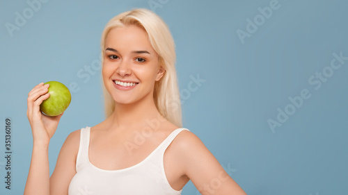 Woman with Apple. Beautiful girl with white smile on a blue background, healthy teeth. High Resolution Image