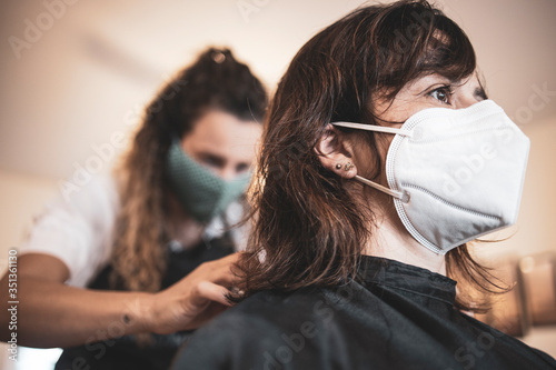 Hairdresser using face mask for the covid-19, new normality, social distance, hairdresser and client at client's home with mask cutting hair. photo