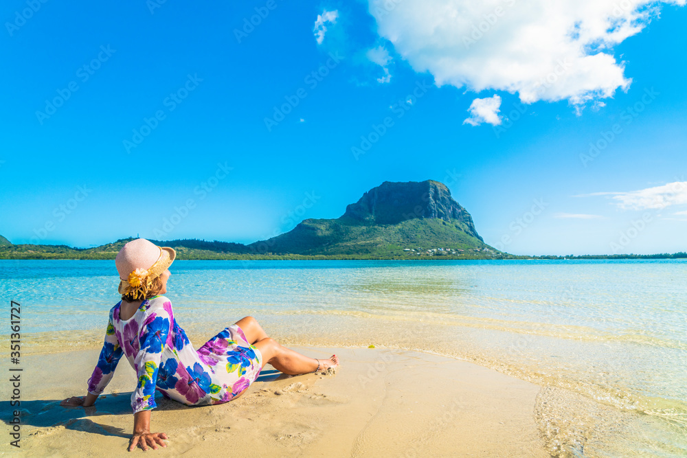 Woman in bright dress relaxing on tropical beach, La Gaulette, Le Morne Brabant, Mauritius, Indian Ocean, Africa Woman in bright dress relaxing on tropical beach, La Gaulette, Le Morne Brabant, Mauritius, Indian Ocean, Africa