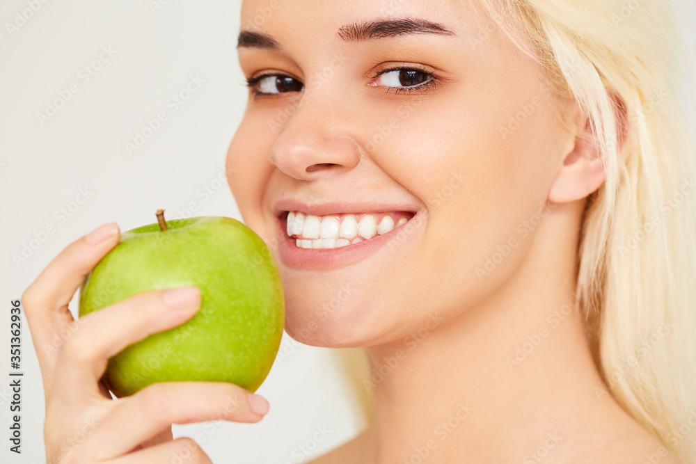 Woman with Apple. Beautiful girl close up with white smile on a gray background, healthy teeth. High Resolution Image Woman with Apple. Beautiful girl close up with white smile on a gray background, healthy teeth. High Resolution Image