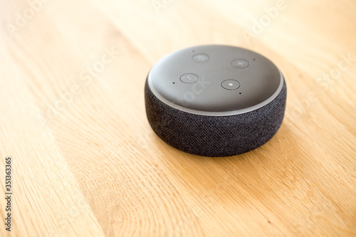 Smart speaker on wooden table desk, smart home assistant device