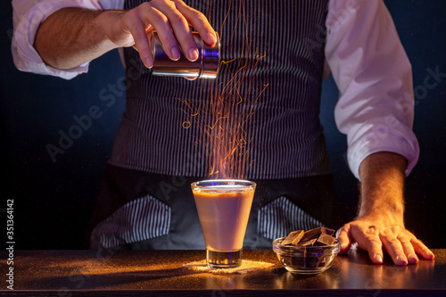 Bartender making Baileys comet cocktail on fire