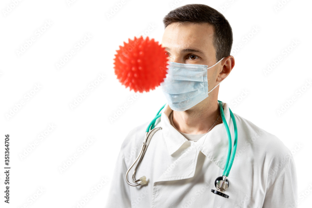 Portrait of a doctor with a stephoscope in a medical mask isolated on white background. Model of an abstract strain of the virus of coronavirus disease COVID-19. Portrait of a doctor with a stephoscope in a medical mask isolated on white background. Model of an abstract strain of the virus of coronavirus disease COVID-19.