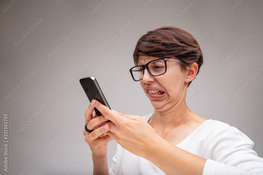 Woman reacting in revulsion to her mobile phone Woman reacting in revulsion to her mobile phone