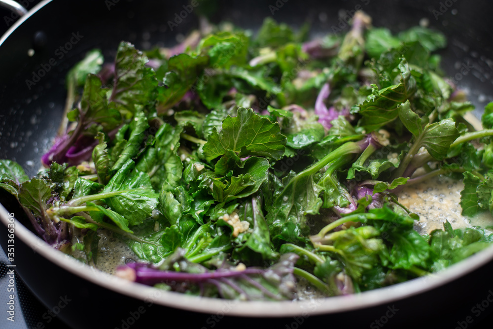 Sautéed kalettes, cooked in butter and garlic in a black pan. Sautéed kalettes, cooked in butter and garlic in a black pan.