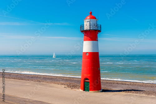Sailship passing the Lighthouse in Westkapelle, Zeeland province, Netherlands. Westkapelle is a small city with about 2,600 inhabitants. The 16 meter tall cast iron lighthouse was built in 1875.