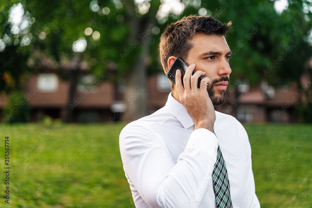 Young business man with white shirt and tie in outdoor park making phone call Young business man with white shirt and tie in outdoor park making phone call