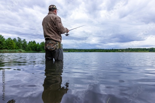 angler catching fish in the lake during cloudy day