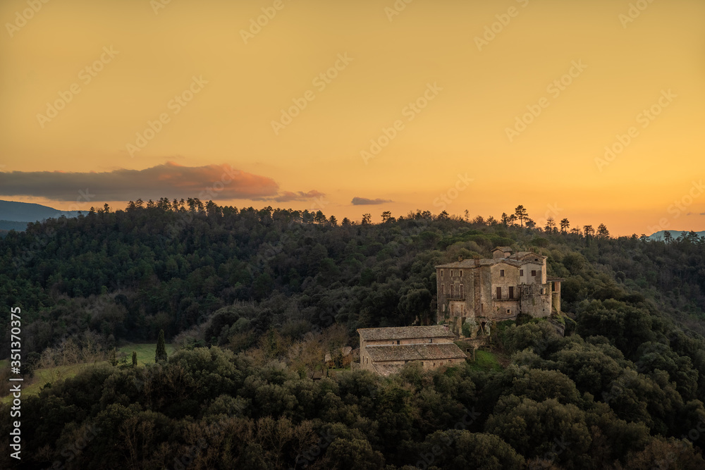 Medieval Spanish castle in forest with setting sun creating a firey yellow sky.