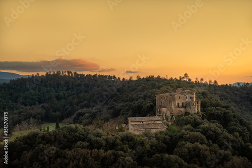 Medieval Spanish castle in forest with setting sun creating a firey yellow sky.