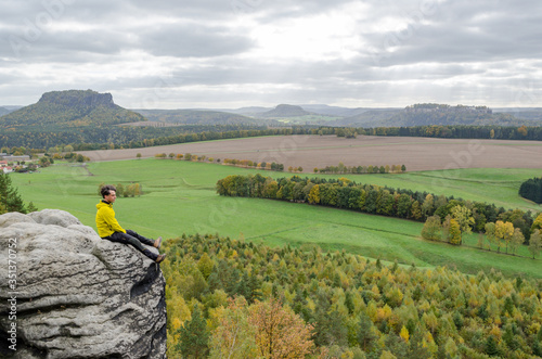 Deutschland, Sachsen, Sächsische Schweiz, Wanderung von Wehlen über die Rauensteine, Wanderer sitzt am Felsen über dem Abhang, Blick von den Rauensteinen auf den Lilienstein